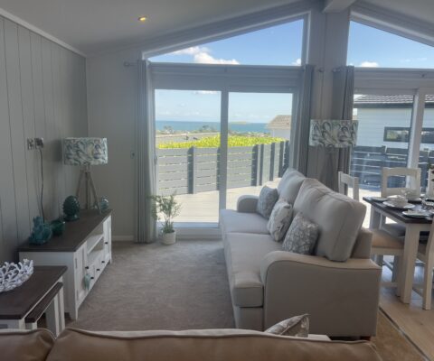 Behind a large sofa you can see two large sliding doors leading out onto a spacious sundeck with seaviews