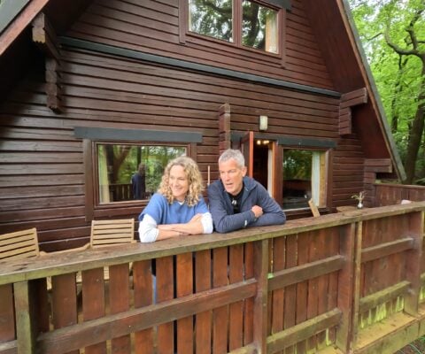 A-frame woodland lodge with couple looking out on the decking area.