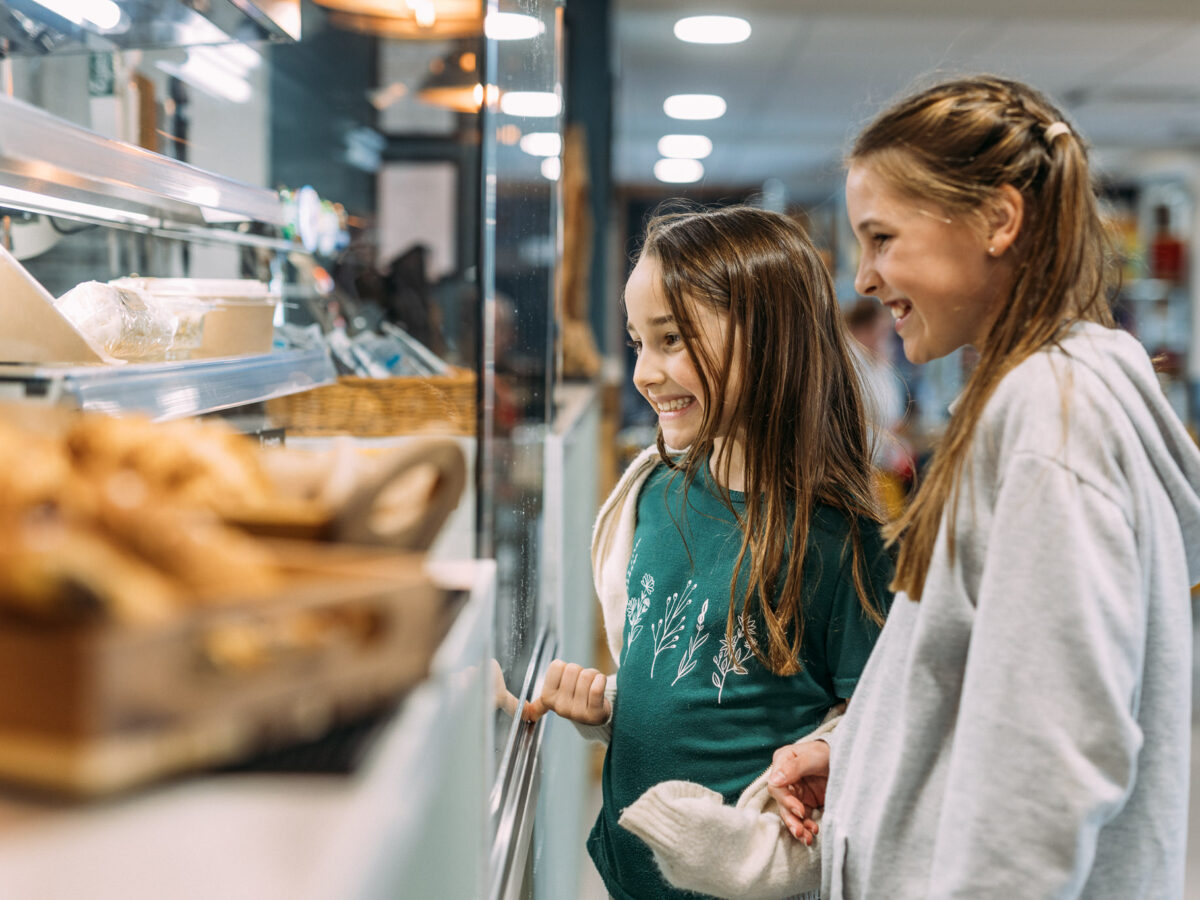Two girls smiling while looking at a selection of food to buy at The Hive Cafe